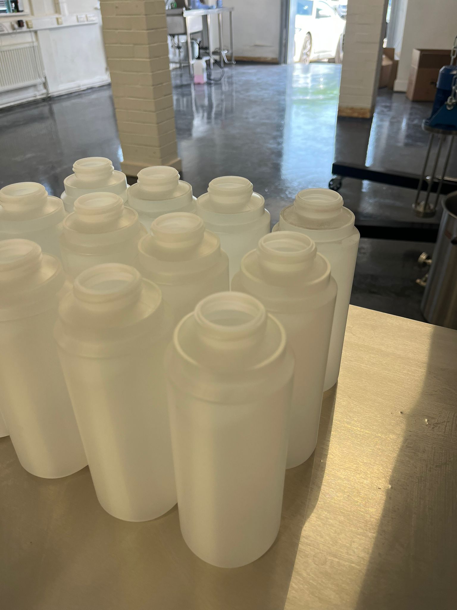 Empty HDPE bottles staged on the bench before a food or beverage production run.