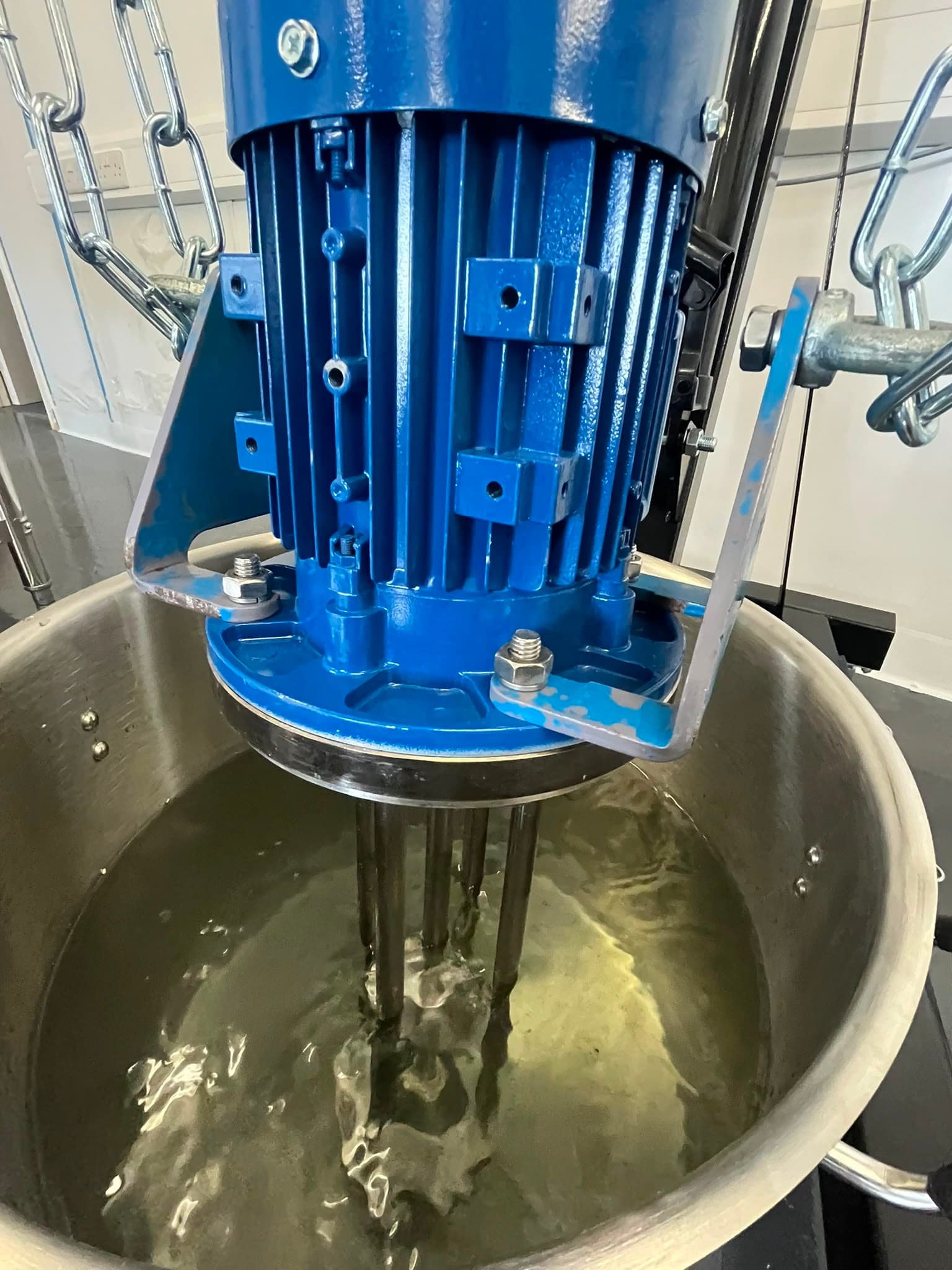 Blue high-shear motor over a stainless mixing vessel - Commercial plant equipment for stable scaled batches.